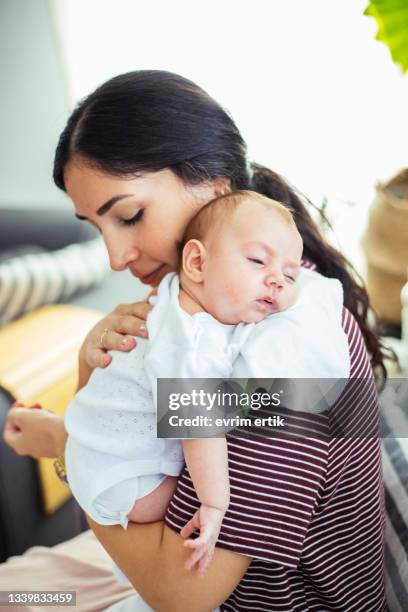 mutter hält das baby zum aufstoßen über die schulter - burping stock-fotos und bilder