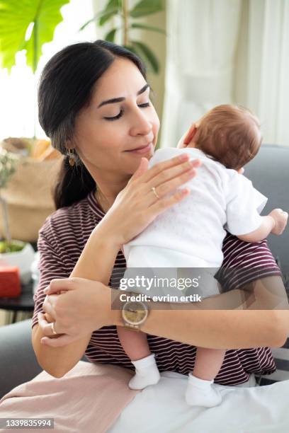 glückliche mutter rülpst ihr schlafendes baby - burping stock-fotos und bilder