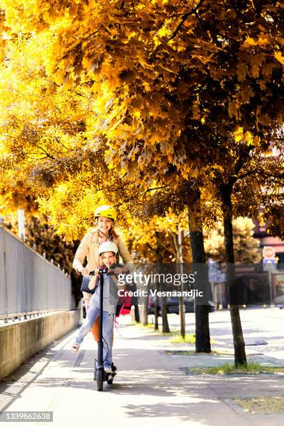 little girl with mother arriving at school on electric scooter - safe kids day arrivals stock pictures, royalty-free photos & images