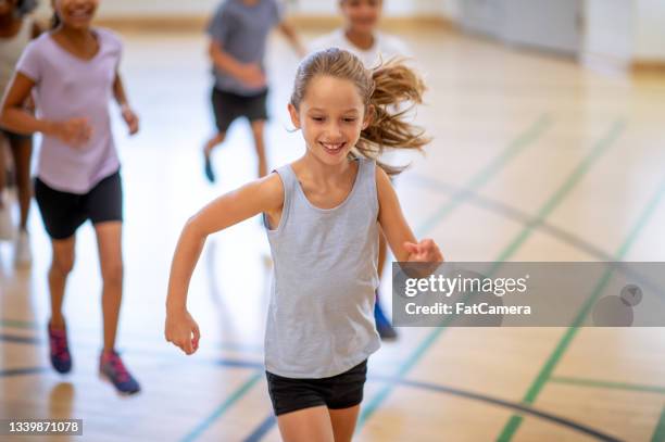 caucasian girl running inside a gym during gym class - ymca stock pictures, royalty-free photos & images