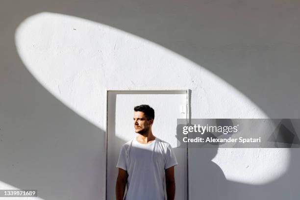 portrait of a young man in white t-shirt against white background - dispersa imagens e fotografias de stock