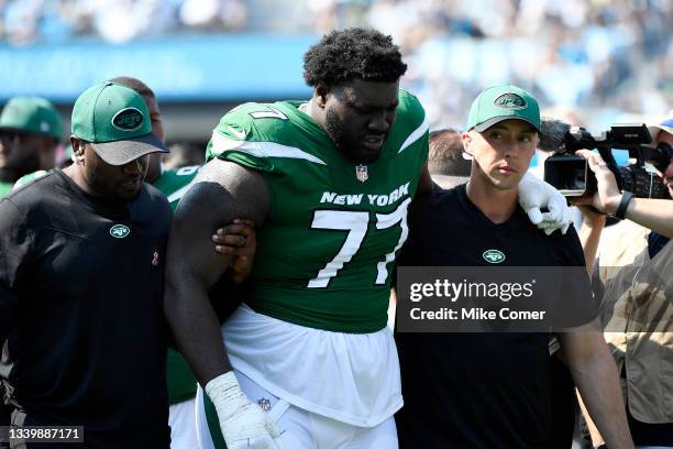 Mekhi Becton of the New York Jets is helped off the field after being injured during the third quarter against the Carolina Panthers at Bank of...