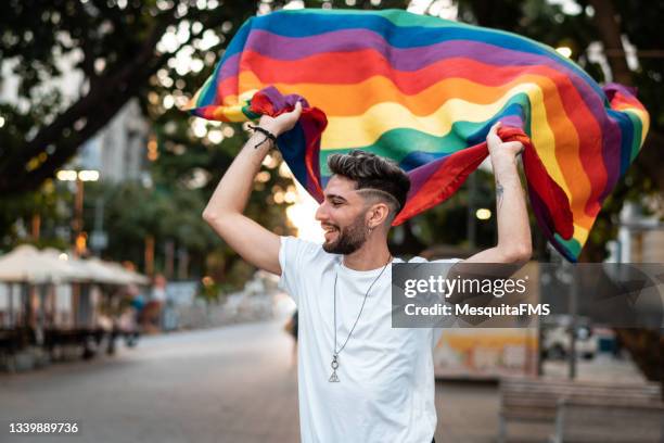 gay young man hold rainbow flag - person holding a flag stock pictures, royalty-free photos & images