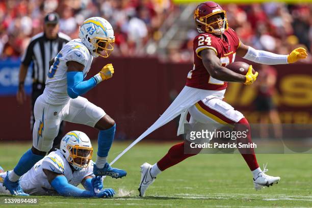 Antonio Gibson of the Washington Football Team rushes past Michael Davis and Kyzir White of the Los Angeles Chargers during the first quarter at...