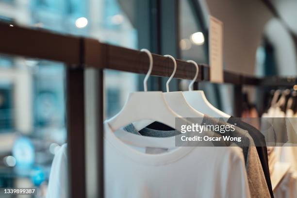 clothes hanging on rack in fashion store - kleiderbügel stock-fotos und bilder