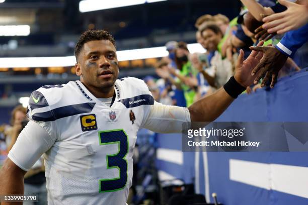 Seattle Seahawks quarterback Russell Wilson high fives with fans following the victory against the Indianapolis Colts at Lucas Oil Stadium on...