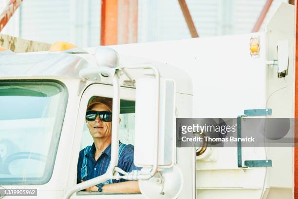 Medium shot portrait of farmer sitting in cab of feed truck on farm