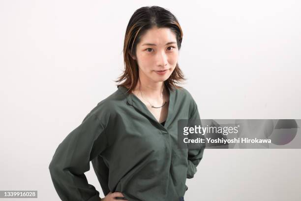 portrait of smiling woman standing in room on white background - 若い女性 日本人 顔 ストックフォトと画像