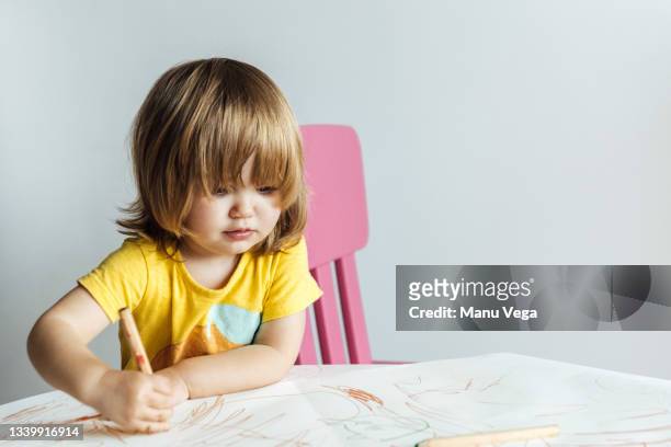 little girl year old boy in yellow t-shirt writing carefully with colors - 2 year old child fotografías e imágenes de stock