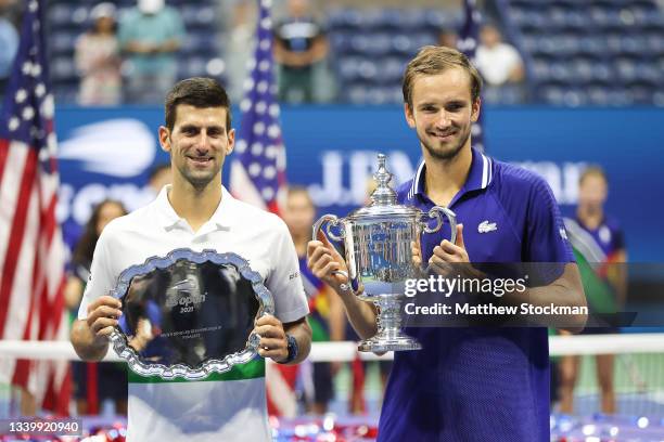 Novak Djokovic of Serbia holds the runner-up trophy alongside Daniil Medvedev of Russia who celebrates with the championship trophy after winning...