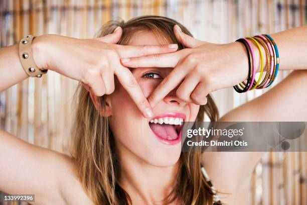 woman looks through triangle made with her fingers - finger frame stock pictures, royalty-free photos & images