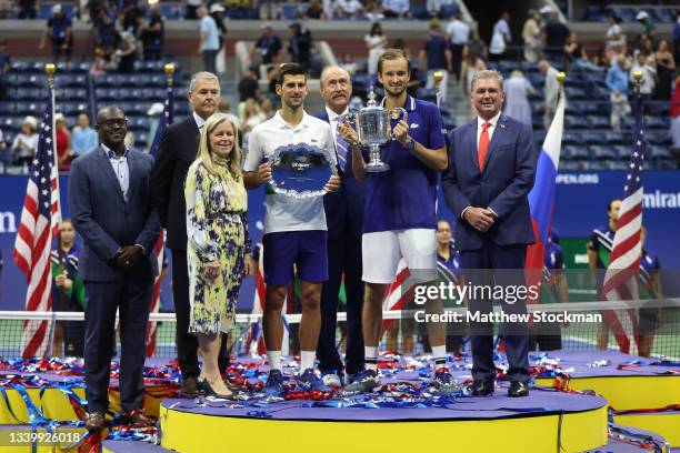 Novak Djokovic of Serbia holds the runner-up trophy alongside Daniil Medvedev of Russia who celebrates with the championship trophy after winning...