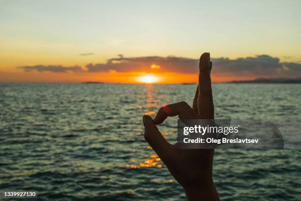 ok, okay, yes sign, made by hand at sunset. feeling good on tropical island. - aura foto e immagini stock