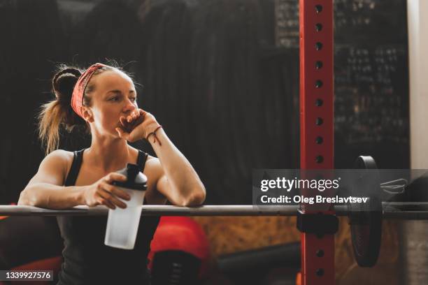 woman tired after weightlifting workout and holding reusable bottle with drinking water - female exercise bildbanksfoton och bilder