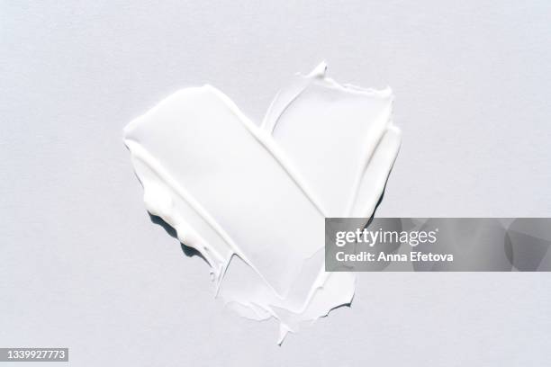textured smears of white cream applied on white background in heart shape. body lotion for perfect skin. macrophotography in flat lay style - hair conditioner texture stock pictures, royalty-free photos & images