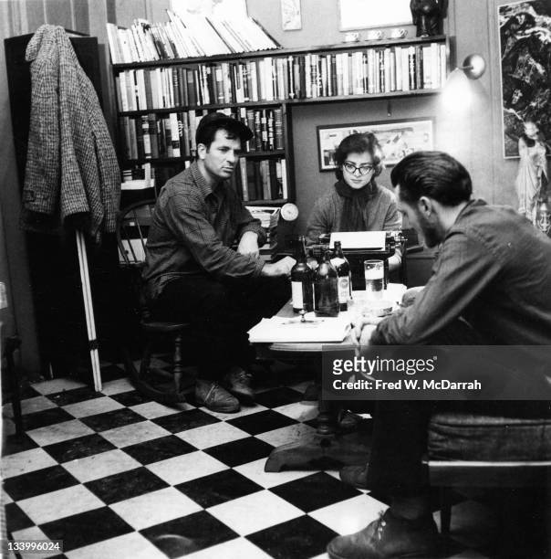 American writers Jack Kerouac and Lew Welch sit around a low table as they collaborate on a poem, which is typed by Gloria Schoffel in the apartment...