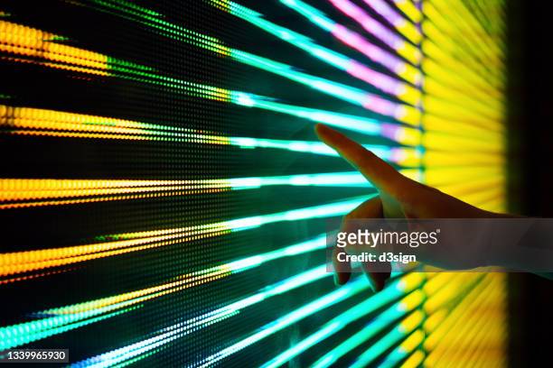close up of woman's hand touching illuminated and multi-coloured led display screen, connecting to the future - gender development stock-fotos und bilder