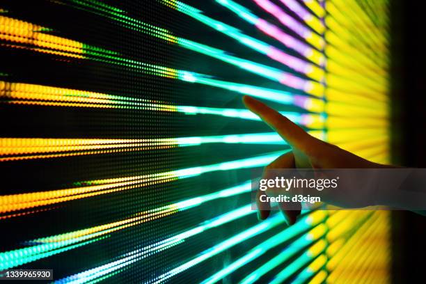 close up of woman's hand touching illuminated and multi-coloured led display screen, connecting to the future - interattività foto e immagini stock