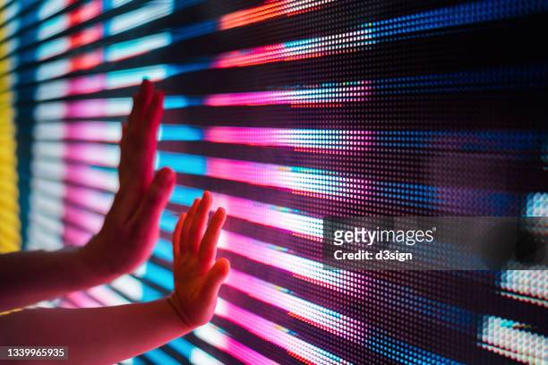 close up of a mother and kid's hand touching illuminated and multi-coloured led display screen, connecting to the future - illuminated stock pictures, royalty-free photos & images