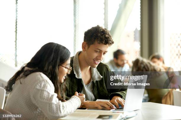 smiling students studying over laptop in cafeteria - estudiantes universitarios bogota fotografías e imágenes de stock