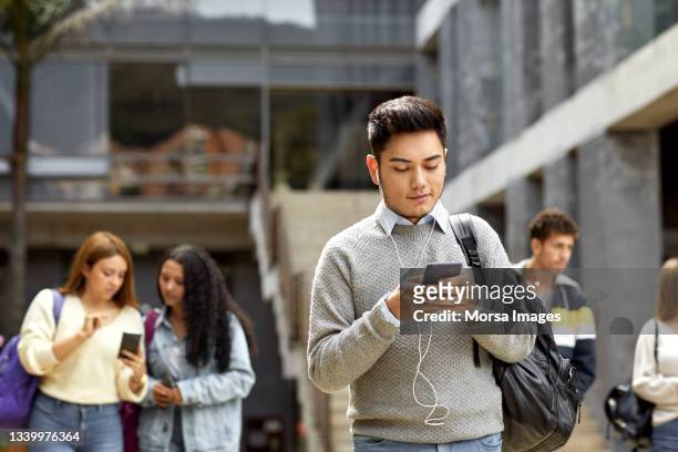 student texting from cell in university campus - digital campus stock pictures, royalty-free photos & images