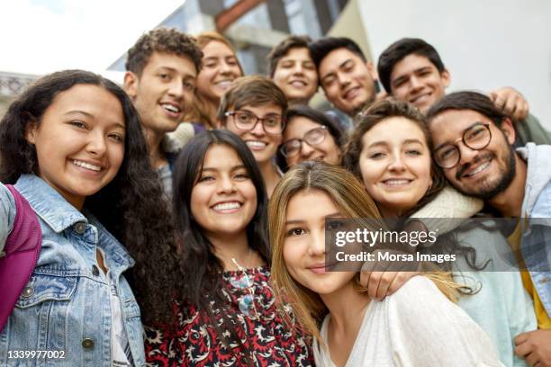 smiling students standing in university campus - adolescence stock pictures, royalty-free photos & images