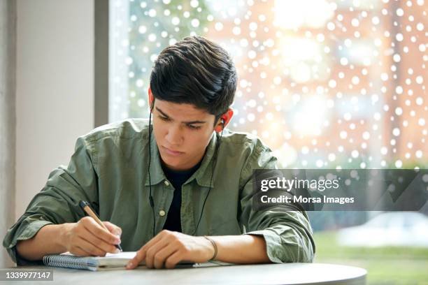 university student studying while wearing headphones in cafeteria - student writing stock pictures, royalty-free photos & images