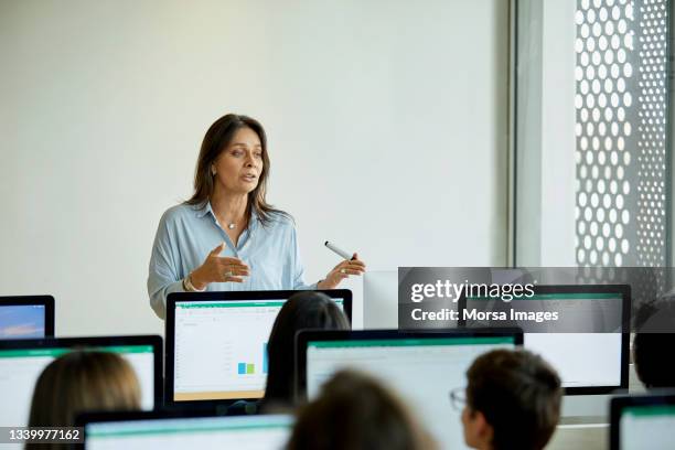 female professor teaching students in computer lab - computer lab stock-fotos und bilder