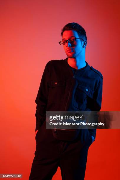 studio portrait of a stylish man with glasses, on a red background - night of fashion for a cause to benefit stomp out bullying stockfoto's en -beelden