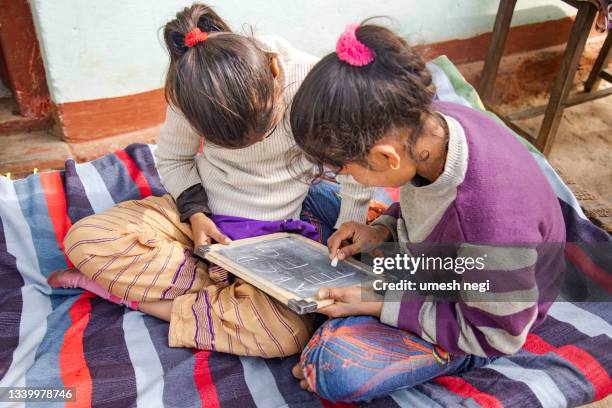 schulmädchen der indischen dorfregierung, das auf schwarzem schiefer zeichnet und schreibt - halbnahe-einstellung stock-fotos und bilder