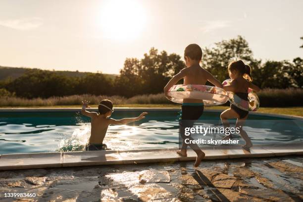 rear view of playful kids jumping into the swimming pool. - backyard pool bildbanksfoton och bilder