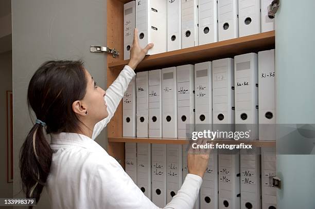 young female assistant looks for folders into a doctor's office - nail file stock pictures, royalty-free photos & images