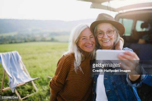 senior women friends taking selfie outdoors in nature, caravan trip holiday. - active senior 個照片及圖片檔