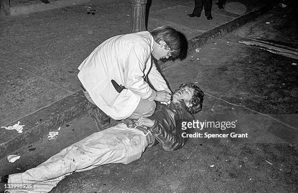 During an anti-war demonstration in Harvard Square, a volunteer paramedic tends to an injured protestor lying on the street, Cambridge,...