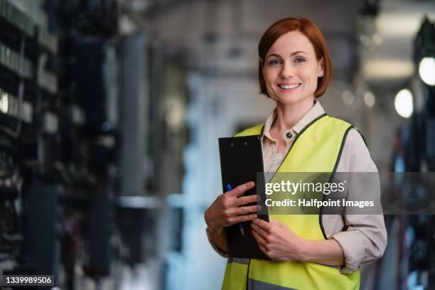 female control engineer checking electrical operating system at control room indoors in power station, looking at camera. - akte aufsicht stock-fotos und bilder