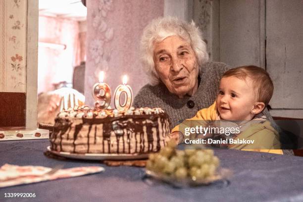 grandma celebrating 90th anniversary birthday with baby grandchild. - 90 birthday stock pictures, royalty-free photos & images