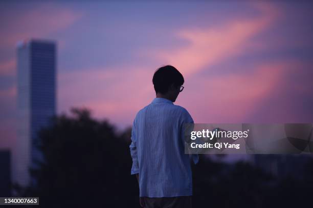 rear view of businessman using smartphone at dusk - purple sunset stock pictures, royalty-free photos & images