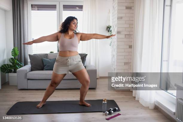 portrait of beautiful young overweight woman indoors at home,  doing exercise. - body conscious stock pictures, royalty-free photos & images