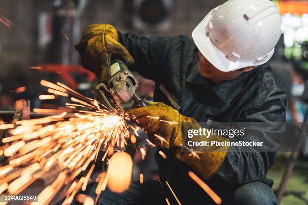 man worker using grinder to polish the metal surface in the workshop. - ferronnerie photos et images de collection