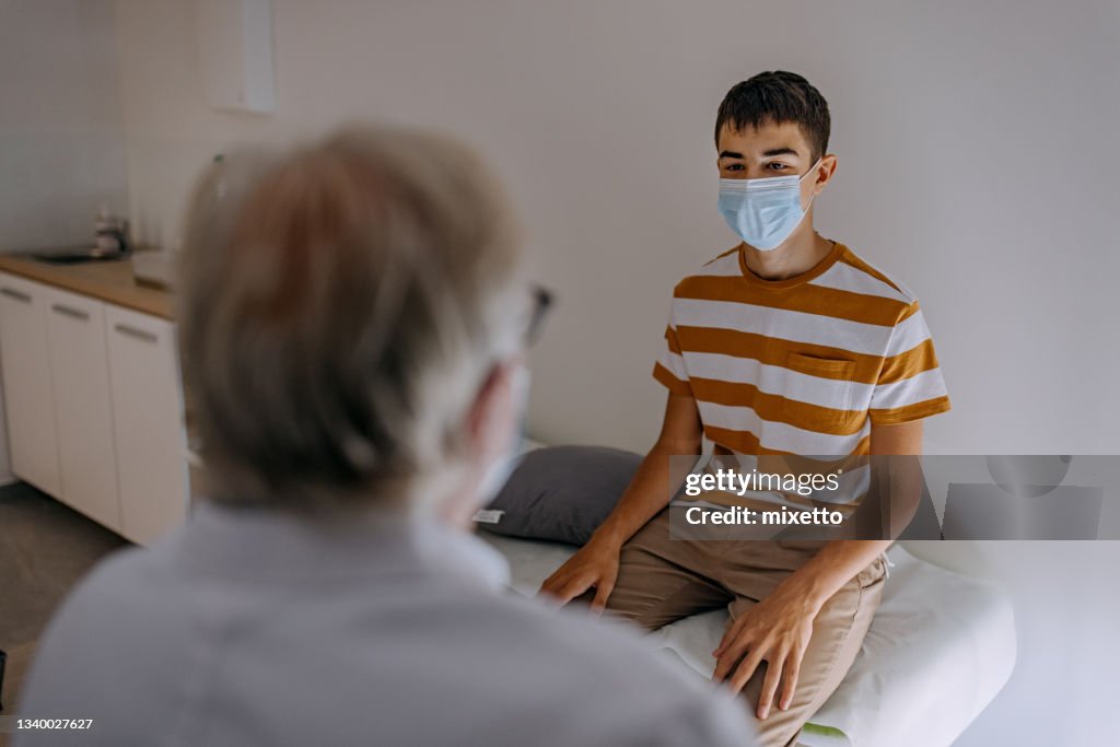 Doctor at hospital wearing mask taking care of young patient