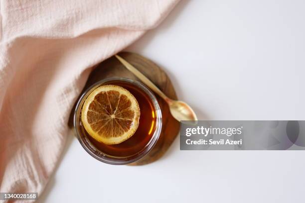 glass of black tea with dried orange slices on wooden coaster on white background. - tea glass table bildbanksfoton och bilder