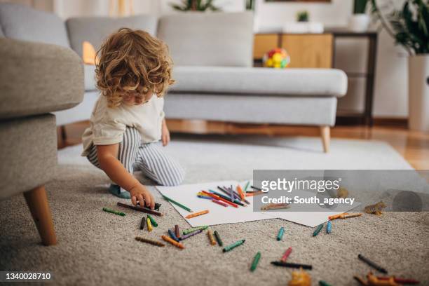 little boy drawing and coloring in the living room on the floor - child playing in room stockfoto's en -beelden