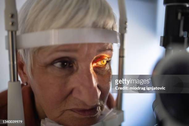 senior woman undergoing eye exam at ophthalmologist office - retinal scan stock pictures, royalty-free photos & images
