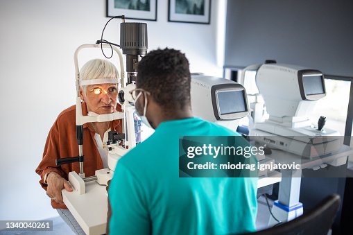 Senior woman undergoing intraocular pressure exam at optometrist office Senior woman undergoing intraocular pressure exam at optometrist office