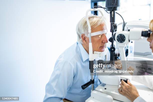 senior man having an eye exam at ophthalmologist's office - eye exam stockfoto's en -beelden