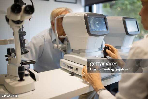 optometrist examining patient's eyes on regular eye exam at medical clinic - retinal scan stock pictures, royalty-free photos & images