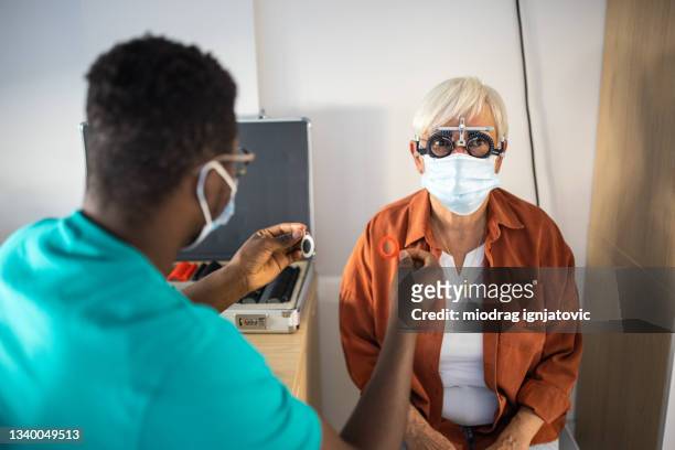 senior woman undergoing vision check with special ophthalmic glasses at medical clinic - special screening of lemony snickets a series of unfortunate events stockfoto's en -beelden