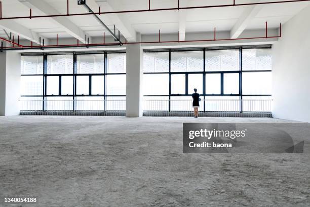 woman standing in new office building - business women looking at new office space stockfoto's en -beelden