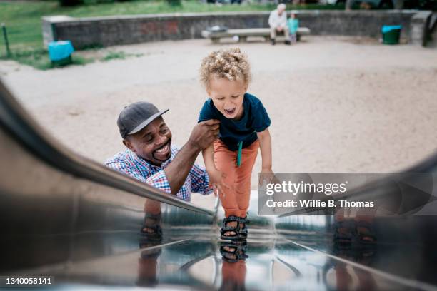 grandfather helping grandson up slide - public park playground stock pictures, royalty-free photos & images