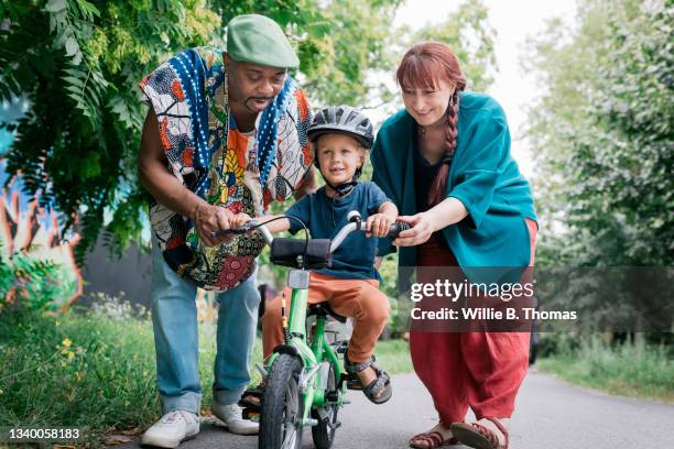 grandparents helping grandson with first bike ride - baby sturzhelm stock-fotos und bilder